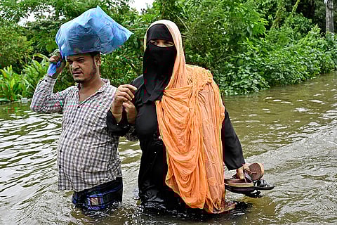Bangladesh Floods: People walk to a relief shelter through a flooded street in Mohipal, Feni district